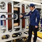 試作機の磁場が発生する空洞部を指さす野村航大さん（左）と鷲野将臣さん＝尼崎市塚口本町８、三菱電機先端技術総合研究所