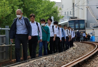 避難誘導訓練で駅間に止まった電車から降り、線路上を歩く人ら＝６日午後、神戸市兵庫区