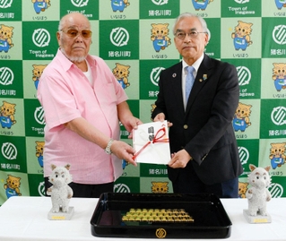 清水三造さん（左）から寄贈を受け取る岡本信司町長（いずれも猪名川町提供）