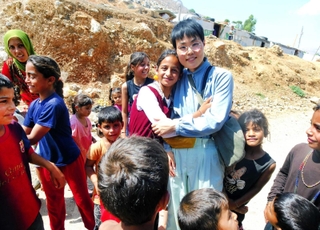 シリアとの国境付近で、難民キャンプの子どもたちに囲まれる佐々木美和さん＝８月、レバノン（神戸国際支縁機構提供）