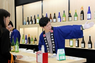 ＬＩＮＥの友だち登録で日本酒を１杯試飲ができる灘五郷のブース。木のぬくもりを感じられる空間に各社の酒瓶が並んだ＝大阪市住之江区南港北１