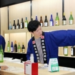 ＬＩＮＥの友だち登録で日本酒を１杯試飲ができる灘五郷のブース。木のぬくもりを感じられる空間に各社の酒瓶が並んだ＝大阪市住之江区南港北１