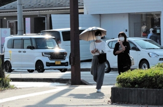 日差しが照りつけ、日傘を差す人も＝豊岡市元町