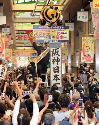 日本シリーズ用のマジックナンバーを「祝３８年ぶり日本一」に切り替え、盛大に祝う阪神ファンら＝６日午前、尼崎市神田中通（撮影・吉田敦史）