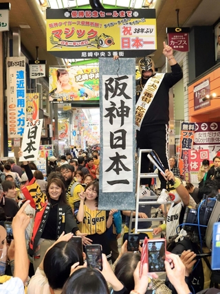 日本シリーズ用に点灯したマジックナンバーを「祝３８年ぶり日本一」の文字に差し替え、盛大に祝う阪神ファンら＝６日午前、尼崎市神田中通３（撮影・吉田敦史）