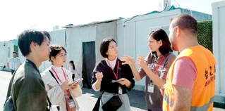 仮設住宅で現地ＮＧＯ職員から話を聞く大学生ら＝トルコ南部（ＣＯＤＥ提供）
