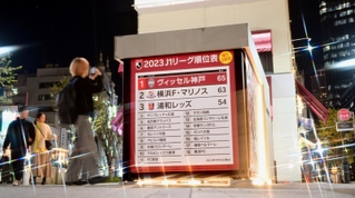 神戸有数の人出でにぎわう元町に登場したＪリーグ順位表。存在感に足を止める姿が目立つ＝神戸市中央区