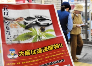 「大麻は違法薬物」と書いたチラシと啓発グッズを受け取る女性＝神戸市中央区布引町、ＪＲ三ノ宮駅