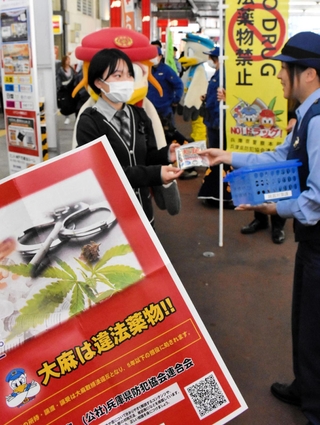 「大麻は違法薬物」と書いたチラシと啓発グッズを受け取る学生＝神戸市中央区布引町、ＪＲ三ノ宮駅