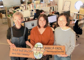 事務所で団体設立当初の看板を手にする吉富志津代さん（中央）、李裕美さん（右）、山口まどかさん＝神戸市長田区海運町３、たかとりコミュニティセンター