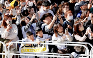 選手を乗せたバスが近づき、一斉にスマートフォンを掲げるオリックスファンら＝２３日午後、神戸市中央区（撮影・大森　武）
