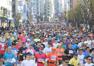 ビルが立ち並ぶ神戸の街中を走り出したランナー＝神戸市中央区