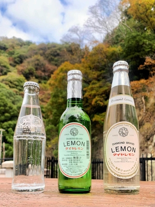 （右から）１０年ほど前まで販売していた透明なリターナブル瓶のダイヤモンドレモン、現在のグリーンの瓶、布引の名水の炭酸水