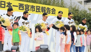 　西宮市役所前で日本一を報告し、園児から花束を受け取った岡田監督（左）と兵庫県出身選手たち（撮影・吉田敦史）