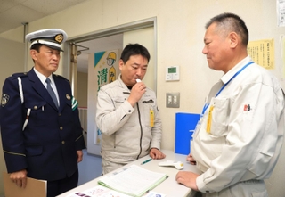 社用車の運転前にアルコール検知器を使う従業員ら。警察官が状況を確認した＝３０日午前、西宮市西宮浜２（撮影・吉田敦史）