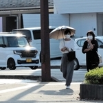 日差しが照りつけ、日傘を差す人も＝豊岡市元町