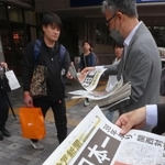 阪神タイガースの３８年ぶり日本一を伝える号外を手に取る通勤客ら＝６日午前、神戸市中央区、ＪＲ神戸駅前（撮影・笠原次郎）