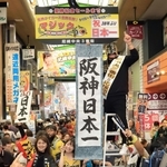 日本シリーズ用に点灯したマジックナンバーを「祝３８年ぶり日本一」の文字に差し替え、盛大に祝う阪神ファンら＝６日午前、尼崎市神田中通３（撮影・吉田敦史）