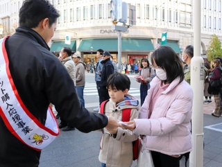 自転車ヘルメットの着用を呼びかけるちらしを手渡す斎藤元彦知事（左）＝神戸市中央区元町通１