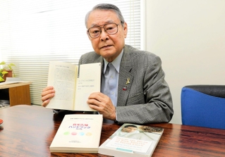 真実告知ハンドブックの改訂版を手にする橋本明・家庭養護促進協会事務局長＝神戸市中央区橘通３