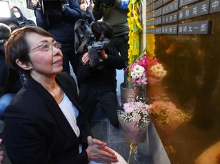 伯母といとこの名前が入った銘板を取り付け、手を合わせる鶴崎光英さん＝１７日午後、神戸市中央区加納町６、東遊園地（代表撮影）