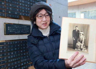 銘板に追加された義父母の写真を手にする佐々木美和子さん＝１７日午後、神戸市中央区加納町６、東遊園地（撮影・笠原次郎）