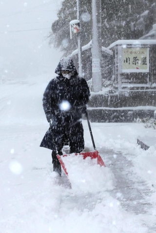 吹雪の中、雪かきする男性＝２１日午前８時５７分、兵庫県香美町香住区下浜（撮影・長谷部崇）