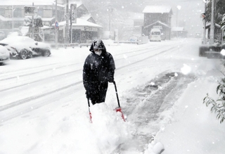 吹雪の中、雪かきする男性＝２１日午前８時５８分、兵庫県香美町香住区下浜（撮影・長谷部崇）