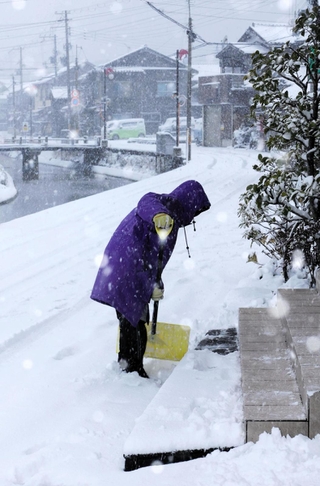 吹雪の中、雪かきする女性＝２１日午前８時４６分、兵庫県香美町香住区下浜（撮影・長谷部崇）