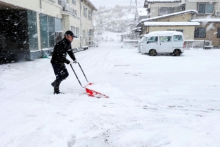 民宿の駐車場を雪かきする男性＝２１日午前、兵庫県香美町香住区下浜（撮影・長谷部崇）