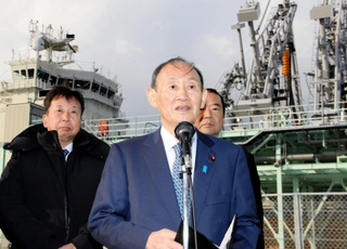 視察先で取材に応じる菅義偉前首相（中央）＝２５日午後、神戸市中央区神戸空港