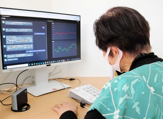 生成ＡＩで最新の手口を再現した特殊詐欺防止訓練ツールを体験する高齢者。動揺などの心情を左手前のモニターで検出する（画面表示は実際と異なる）＝尼崎市役所