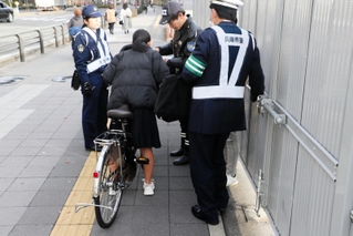 自転車利用者を呼び止め、指導警告書を交付する警察官たち＝２０２３年１２月中旬、尼崎市潮江
