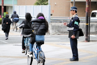 街頭に立って自転車の交通違反を取り締まる警察官たち＝２０２３年１２月中旬、尼崎市潮江