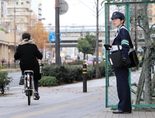 街頭に立って自転車の交通違反を取り締まる警察官たち＝２０２３年１２月中旬、尼崎市潮江