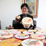 ゴジラやキティちゃん、時には警察とも。さまざまなコラボ商品や特別版の「ひっぱりだこ飯」を持つ柳本雄基副社長＝神戸市東灘区魚先南町３、淡路屋