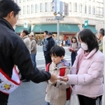 自転車ヘルメットの着用を呼びかけるちらしを手渡す斎藤元彦知事（左）＝神戸市中央区元町通１
