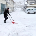 民宿の駐車場を雪かきする男性＝２１日午前、兵庫県香美町香住区下浜（撮影・長谷部崇）