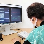 生成ＡＩで最新の手口を再現した特殊詐欺防止訓練ツールを体験する高齢者。動揺などの心情を左手前のモニターで検出する（画面表示は実際と異なる）＝尼崎市役所