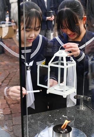 「１．１７希望の灯り」をろうそくで分灯する生徒ら＝７日午後、神戸市中央区加納町６、東遊園地〈撮影・斎藤雅志）