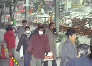 震災後、建物の解体付近を通る市民ら。粉じんが舞い、マスクをする人も多かった＝１９９５年１月３１日、神戸市中央区