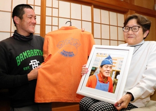 磯谷吉夫さんの写真を手に、阪神・淡路大震災後の歩みを振り返る妻の香代子さん（右）と長男の太朗さん。オレンジのシャツはとんかつ店で着ていたもの＝神戸市灘区稗原町