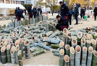 「１・１７」の文字に並べる竹灯籠を準備する神港学園高校の野球部員ら＝神戸市中央区加納町６、東遊園地