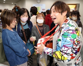 公演後、来場者に募金を呼びかけるシンガー・ソングライターのＴＯＵＭＡさん（右）＝神戸市垂水区日向１、レバンテホール