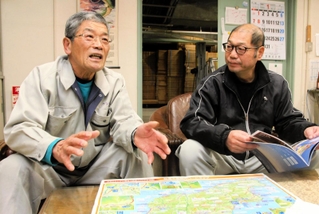 能登半島の地図を見ながら、被災時の様子を語る竹澤茂さん（左）。剣菱酒造の藤田雄一さんも思いを聞き続けた＝神戸市東灘区深江浜町（撮影・高田康夫）
