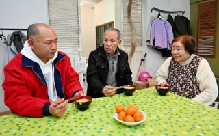 避難先で食卓を囲む大家勉さん（中央）と妻の美智子さん（右）、長男の真一さん＝淡路市下司