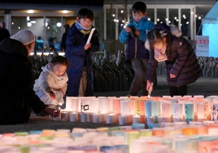 灯籠にろうそくで火をともす子どもら＝１６日午後６時３２分、神戸市中央区加納町６、東遊園地（撮影・斎藤雅志）
