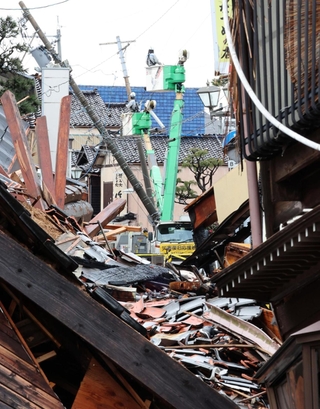 傾いた電柱の周囲で復旧作業が続いていた＝２１日午前、石川県輪島市（撮影・笠原次郎）
