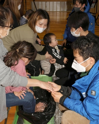 赤ちゃんから祖母まで３世代に足湯する神戸大学の学生。会話を楽しんだ後、祖母が「笑ってんとやっとれん」とつぶやいた＝２０日、石川県七尾市（撮影・笠原次郎）