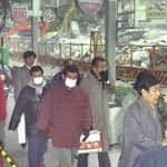 震災後、建物の解体付近を通る市民ら。粉じんが舞い、マスクをする人も多かった＝１９９５年１月３１日、神戸市中央区